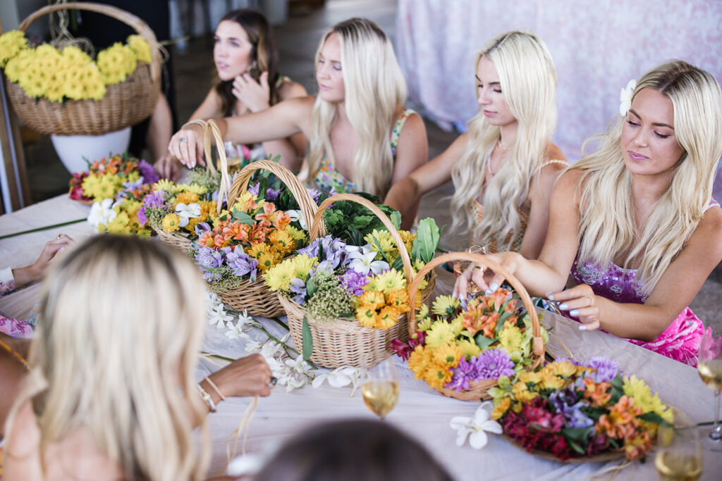 Matias Ezcurra Photography, Women arranging colorful flowers in wicker baskets at a flower arranging workshop.