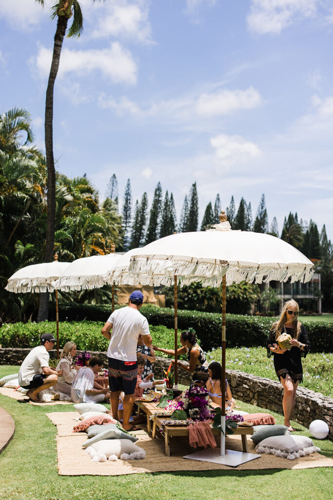 Matias Ezcurra Photography, Guests enjoy a luxurious outdoor luncheon under white umbrellas at an Olowalu Plantation wedding.