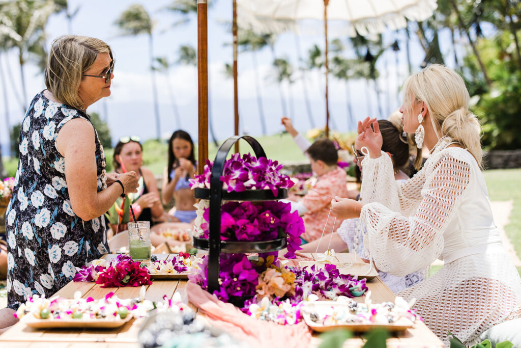 Matias Ezcurra Photography, Guests making flower leis at a Hawaiian wedding luau. Olowalu Plantation wedding weekend.