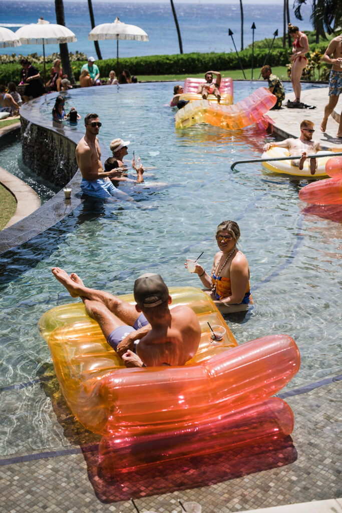 Matias Ezcurra Photography, Guests relax on inflatable pool loungers at an Olowalu Plantation wedding weekend pool party.