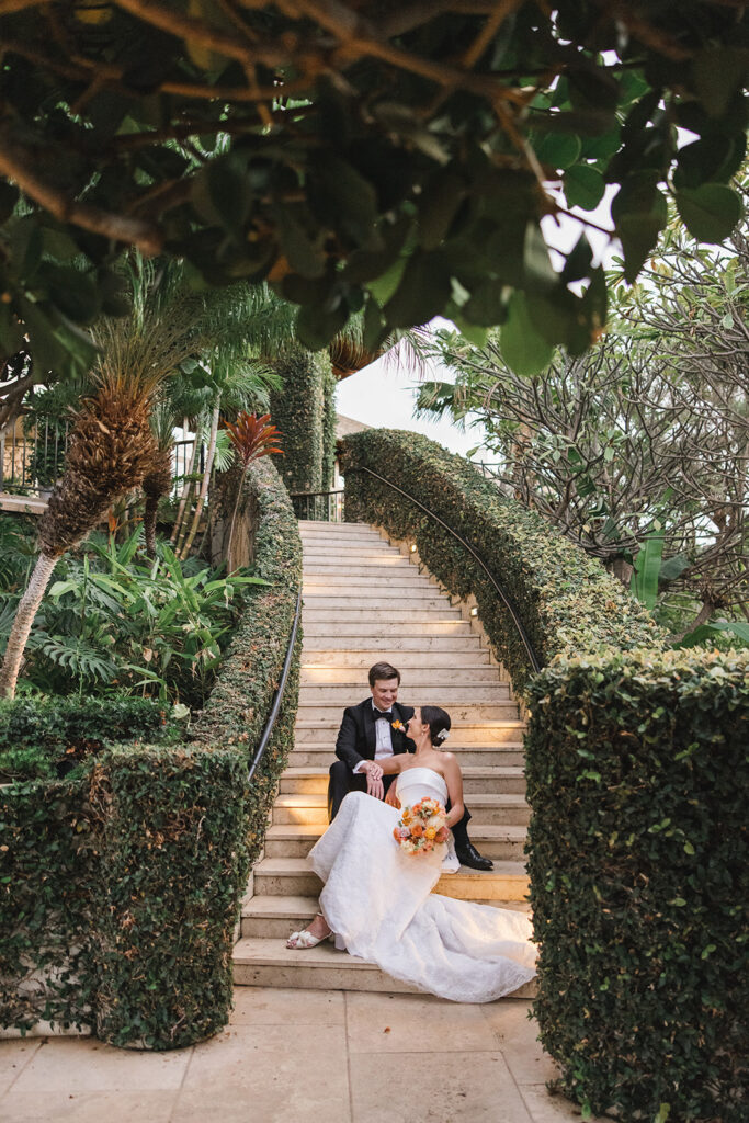 Matias Ezcurra Photography, Bride and groom seated on a lush, outdoor staircase at Hotel Wailea, Maui. Intimate wedding.