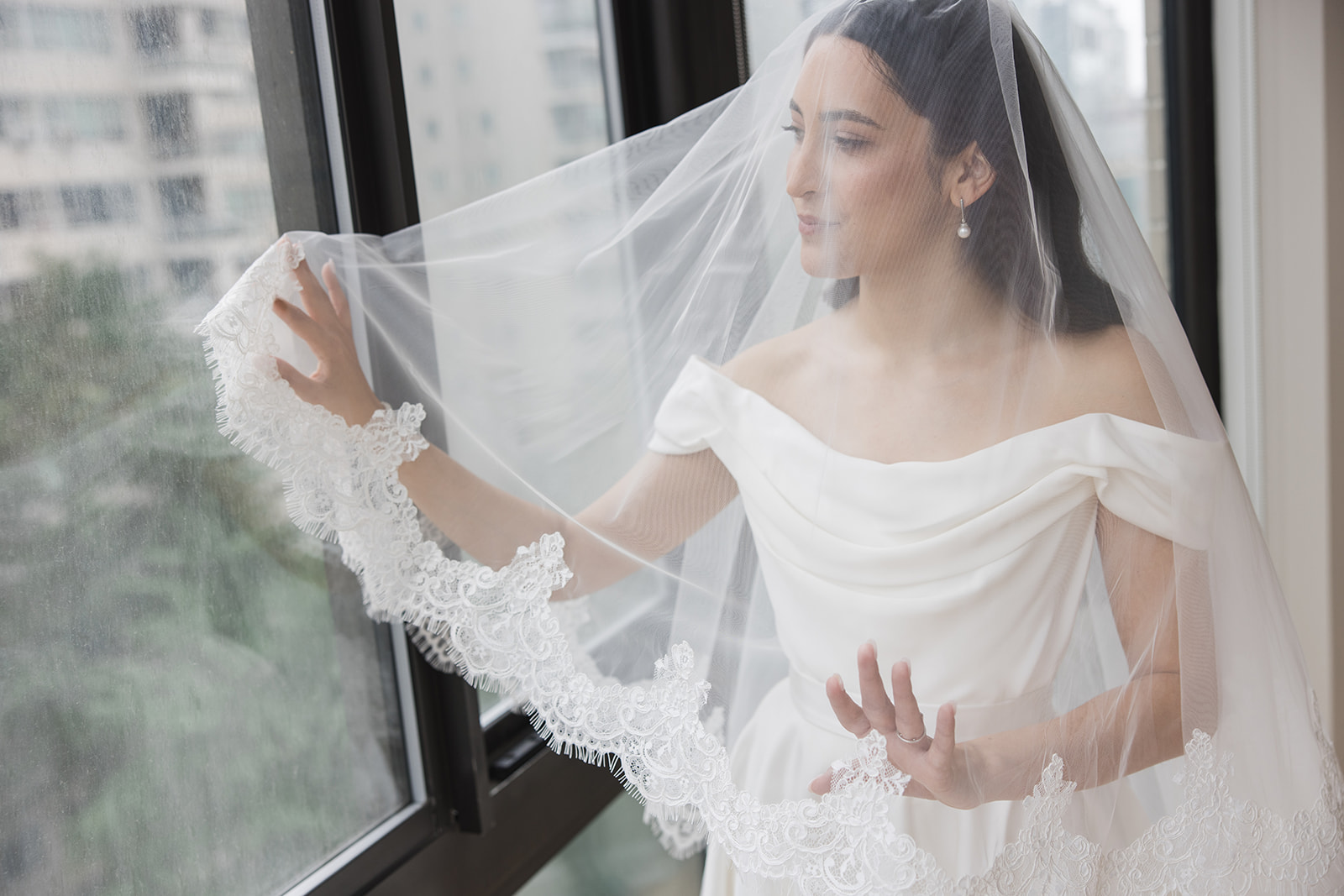 Matias Ezcurra Photography, Bride in off-the-shoulder wedding gown, veiled, looking out window at Wave Hill, New York.