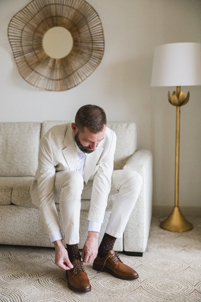 Matias Ezcurra Photography, Groom in a light suit tying his brown leather shoes, Grand Wailea Maui Wedding preparation.