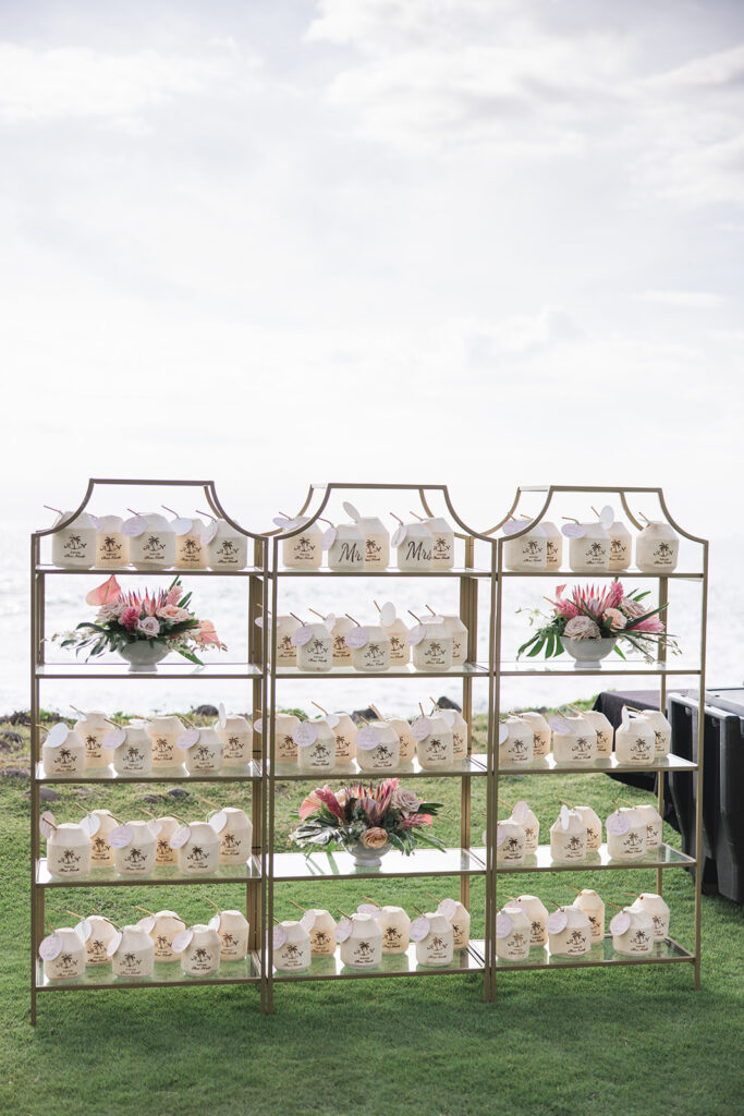Matias Ezcurra Photography, Wedding favors with "Mr. & Mrs." displayed on gold shelves at a Maui venue.