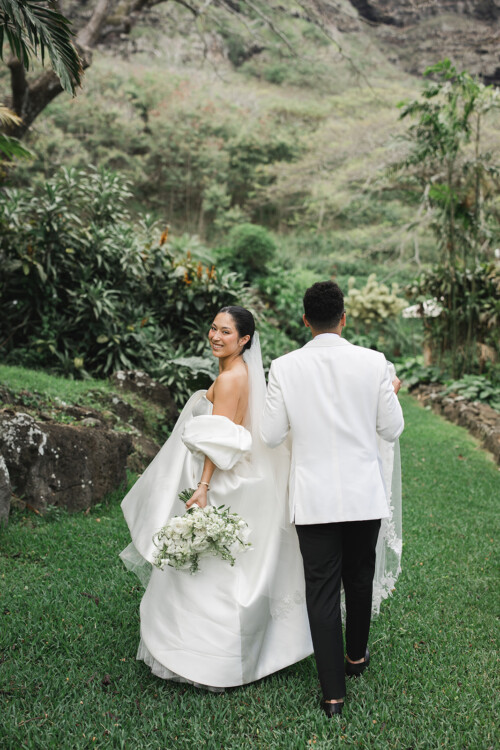 Matias Ezcurra Photography, Bride and groom walking away, Kualoa Ranch wedding. Elegant white dress and suit.