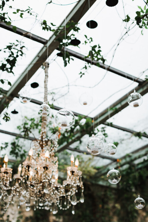Matias Ezcurra Photography, Crystal chandelier and glass globe lights hang from a vine-covered ceiling at a Haiku Mill wedding.