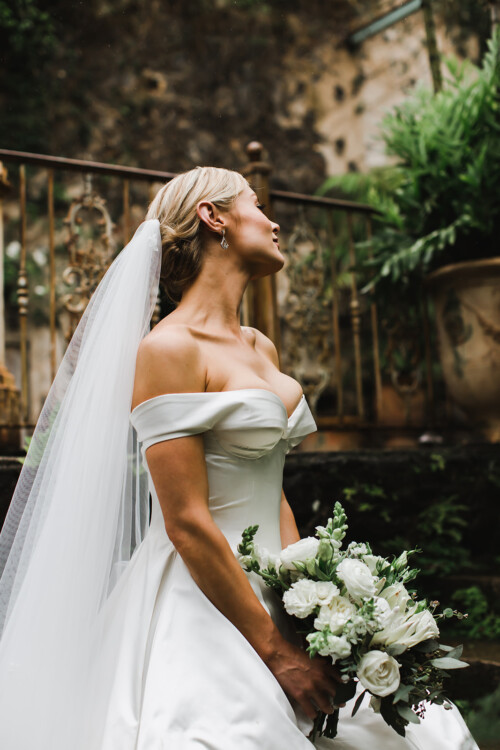 Matias Ezcurra Photography, Bride in off-the-shoulder gown holds wedding bouquet at Haiku Mill.