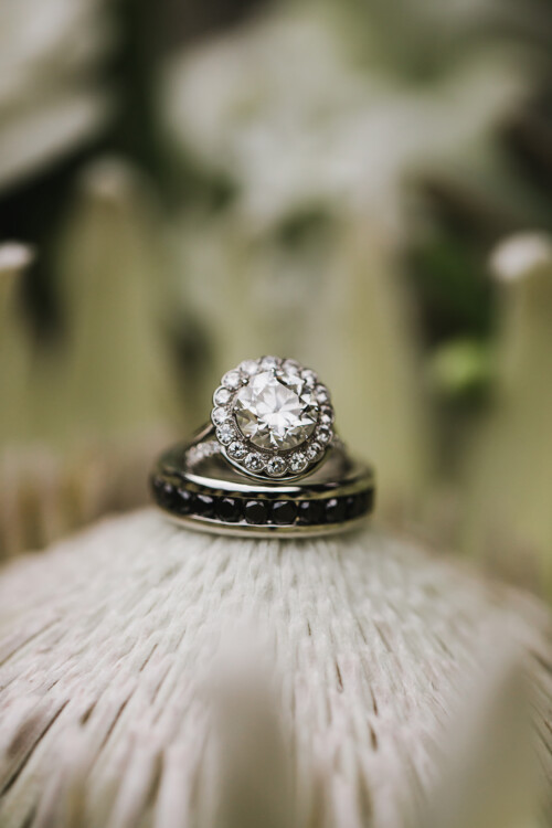 Matias Ezcurra Photography, Close-up of wedding rings on a white flower. Diamond engagement ring and black diamond band.