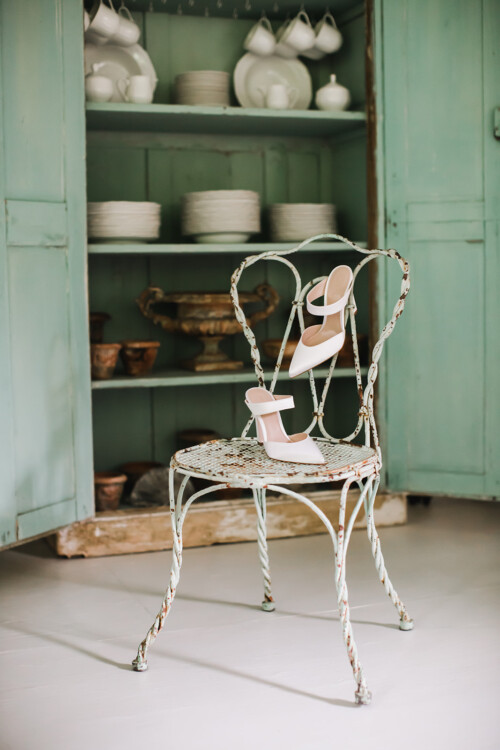 Matias Ezcurra Photography, White wedding shoes on a vintage chair in front of a mint green cabinet.
