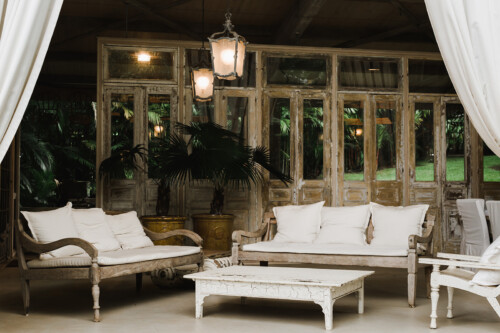 Matias Ezcurra Photography, Rustic lounge area with white cushions and antique wooden furniture at a Haiku Mill wedding.