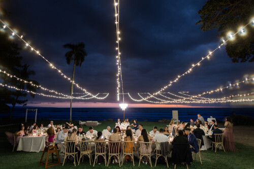 Matias Ezcurra Photography, Wedding reception at sunset, Olowalu Plantation House, Maui. Guests seated at long table under string lights.