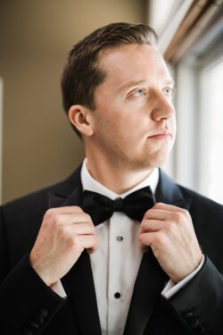 Matias Ezcurra Photography, Groom adjusts bow tie in tuxedo, preparing for Haiku Mill wedding.