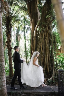Matias Ezcurra Photography, Bride and groom walking through lush garden at Haiku Mill wedding.