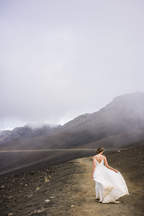 Matias Ezcurra Photography, Bride in flowing white gown walking away on a volcanic landscape.