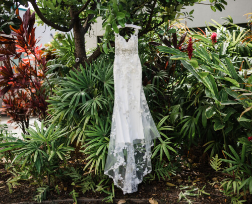 Matias Ezcurra Photography, Bride's wedding dress hangs amidst lush tropical greenery.