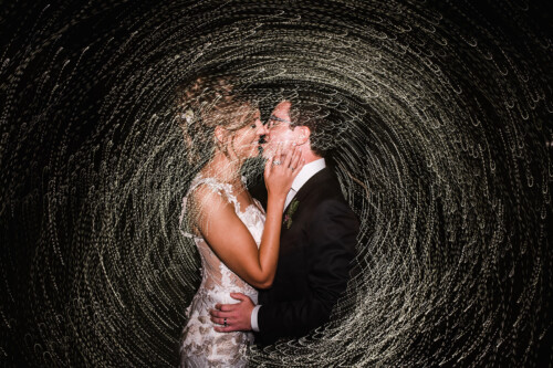 Matias Ezcurra Photography, Bride and groom share a romantic kiss, surrounded by swirling light trails at their wedding.