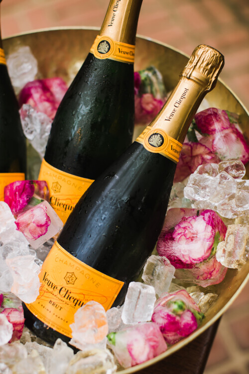 Matias Ezcurra Photography, Veuve Clicquot champagne bottles chilled in a brass bowl with floral ice cubes.
