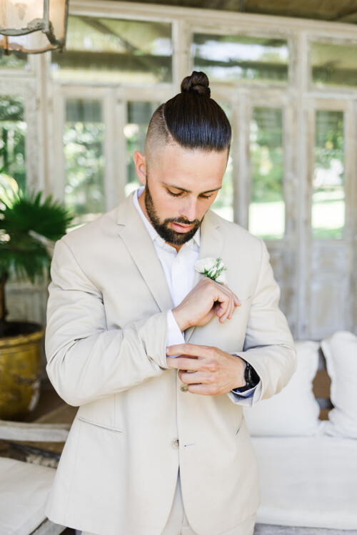 Matias Ezcurra Photography, Groom adjusting cufflinks, wearing a tan suit and man bun at Haiku Mill wedding.