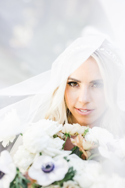 Matias Ezcurra Photography, Bride at Haiku Mill, partially veiled, holding a bouquet of white flowers.