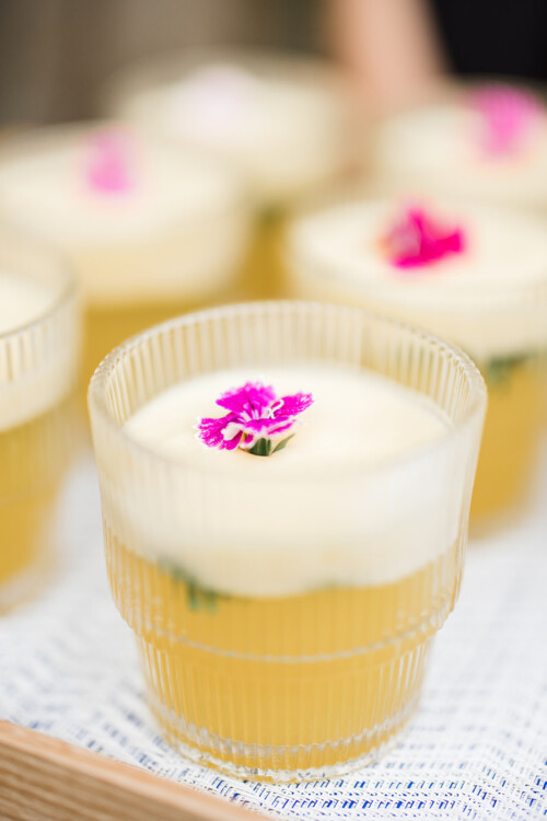Matias Ezcurra Photography, Close-up of refreshing yellow cocktails garnished with pink flowers at a Haiku Mill wedding.