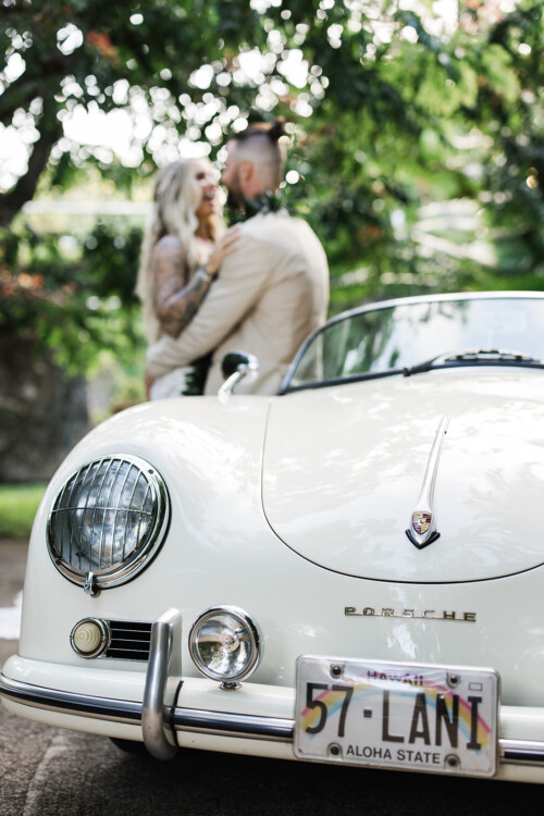 Matias Ezcurra Photography, Vintage white Porsche 356 with "57-LANI" license plate; newlyweds embrace in background.