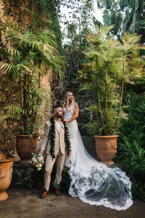 Matias Ezcurra Photography, Bride and groom pose amidst lush tropical plants at Haiku Mill wedding.