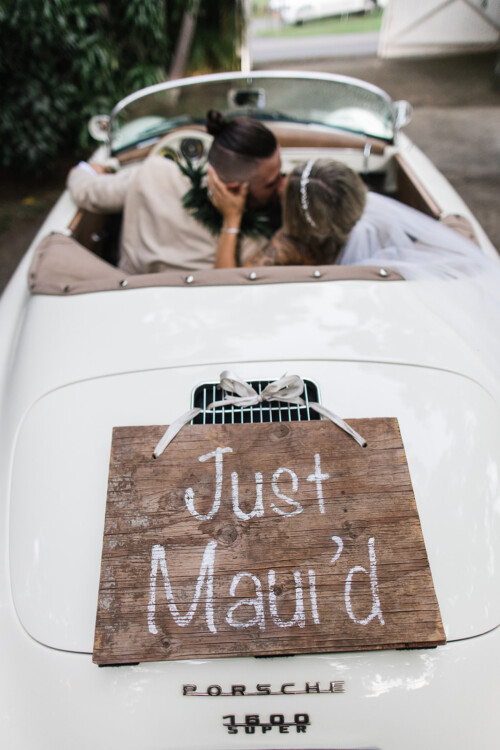 Matias Ezcurra Photography, Newlyweds kiss in a vintage Porsche, "Just Maui'd" sign on back. Haiku Mill wedding.
