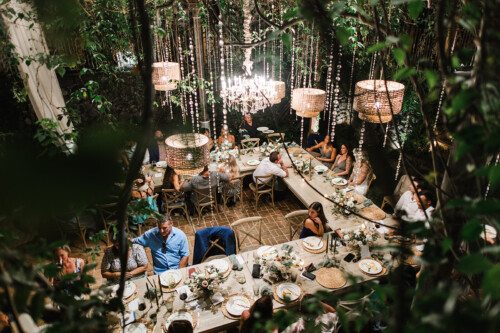 Matias Ezcurra Photography, Overhead view of wedding reception at Haiku Mill, guests seated at long wooden tables under crystal chandeliers and string lights.