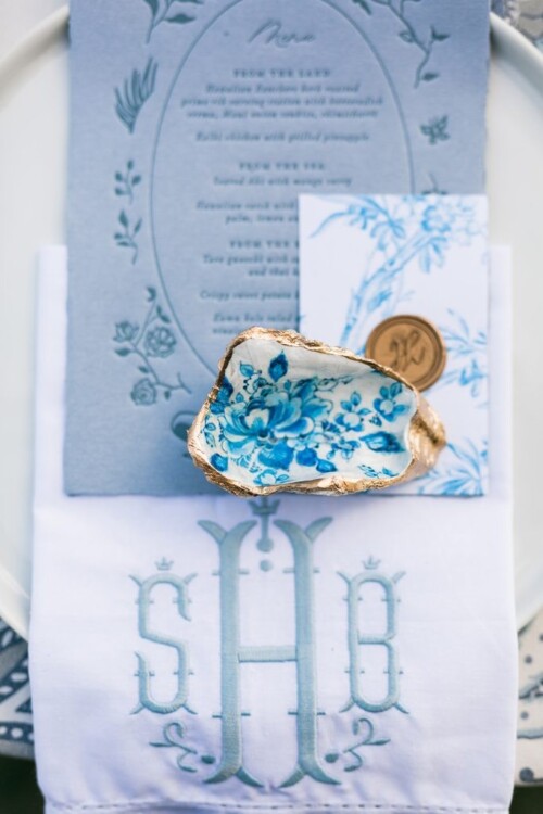 Matias Ezcurra Photography, Blue and white wedding place setting with monogrammed napkin and seashell detail.