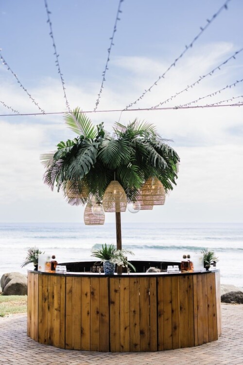 Matias Ezcurra Photography, Circular wooden bar with tropical plants and woven pendant lights at an Olowalu Plantation wedding.