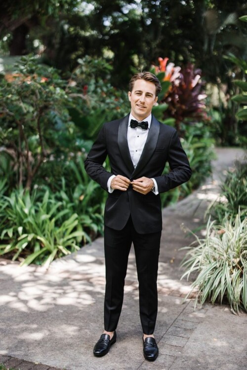 Matias Ezcurra Photography, Groom in black tuxedo, adjusting jacket, Olowalu Plantation wedding.