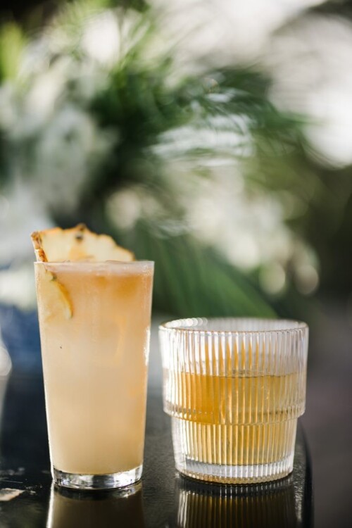 Matias Ezcurra Photography, Two refreshing cocktails on a table, one with pineapple garnish. Olowalu Plantation wedding reception drinks.