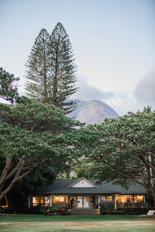 Matias Ezcurra Photography, Olowalu Plantation house at sunset, surrounded by lush greenery and a majestic mountain backdrop. Brooke + Sam's wedding weekend location.