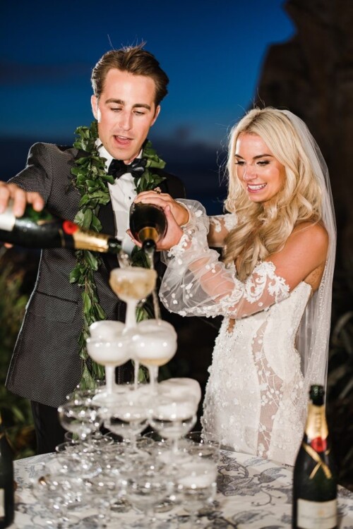 Matias Ezcurra Photography, Bride and groom pouring champagne into a wedding champagne tower at their Olowalu Plantation wedding.