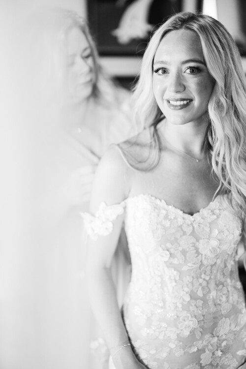 Matias Ezcurra Photography, Bride in lace wedding dress smiles as her mother helps her get ready
