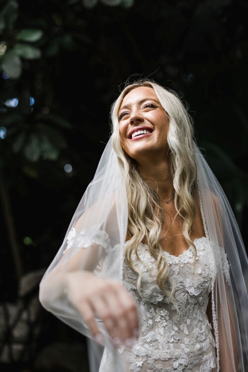 Matias Ezcurra Photography, Happy bride in a lace wedding dress smiles under her veil.