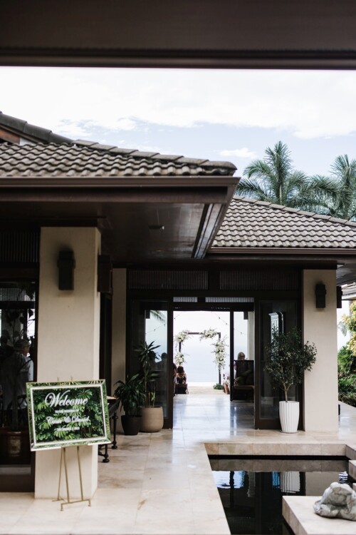 Matias Ezcurra Photography, Welcome sign at tropical wedding ceremony entrance. Guests seated near ocean view.