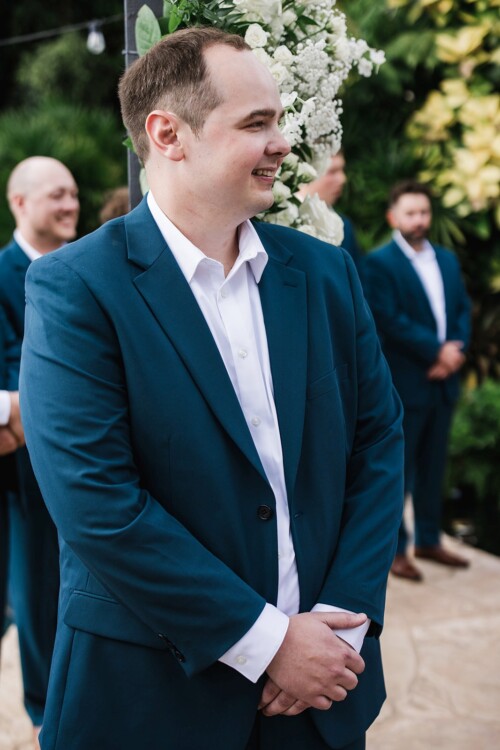 Matias Ezcurra Photography, Groom in teal suit awaits bride at outdoor wedding ceremony.