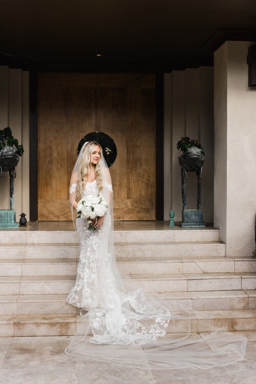 Matias Ezcurra Photography, Bride in lace wedding dress with long veil and white bouquet on stairs
