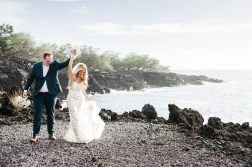 Matias Ezcurra Photography, Happy bride and groom holding hands, walking on a rocky beach near the ocean.