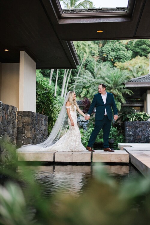 Matias Ezcurra Photography, Bride and groom holding hands, walking on stone path over water feature. Luxury wedding.