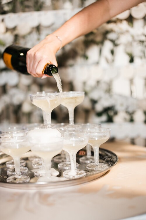 Matias Ezcurra Photography, Hand pouring champagne into a pyramid of glasses for a celebration.