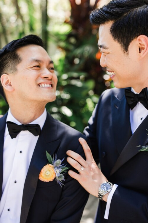 Matias Ezcurra Photography, Two happy grooms in tuxedos embrace before their wedding.
