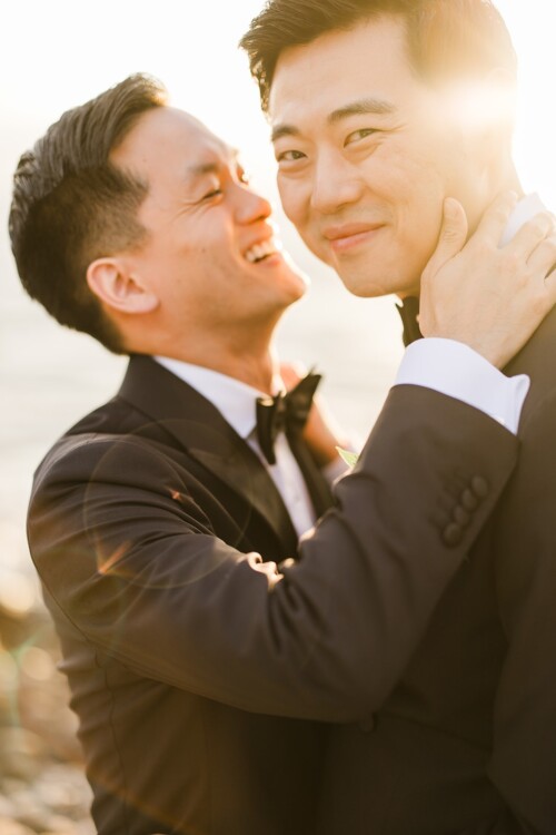 Matias Ezcurra Photography, Happy gay couple embracing at sunset, wearing tuxedos.