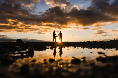 Matias Ezcurra Photography, Silhouette of a couple holding hands at sunset, reflected in a puddle.