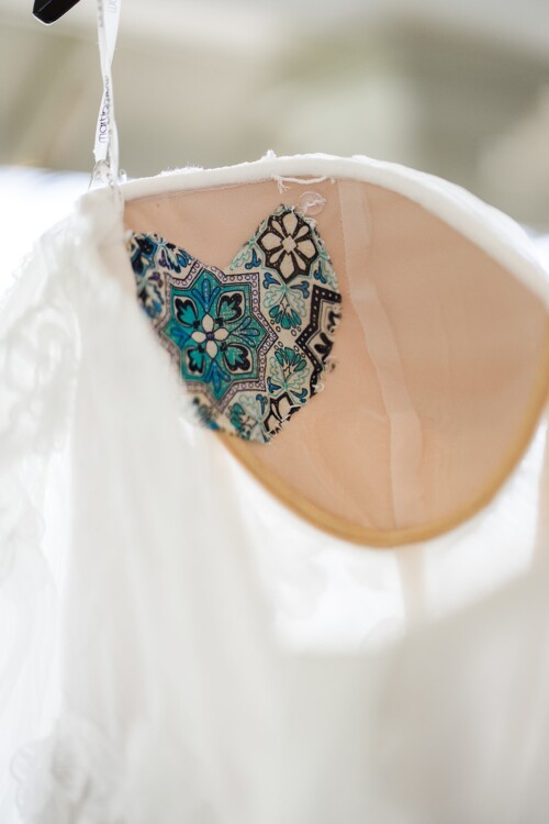 Matias Ezcurra Photography, Close-up of a wedding dress detail: a heart-shaped patch with a teal and white patterned fabric.