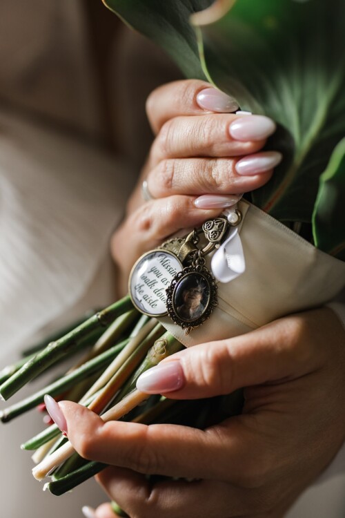 Matias Ezcurra Photography, Bride's hands holding wedding bouquet with memorial charms; "Missing you as you walk down the aisle.