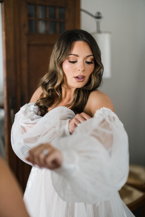 Matias Ezcurra Photography, Bride in off-the-shoulder wedding dress with billowing sleeves, preparing for her wedding at Olowalu Plantation House.