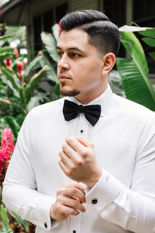 Matias Ezcurra Photography, Groom adjusting cufflinks, wearing tuxedo shirt and bow tie. Olowalu Plantation House wedding.