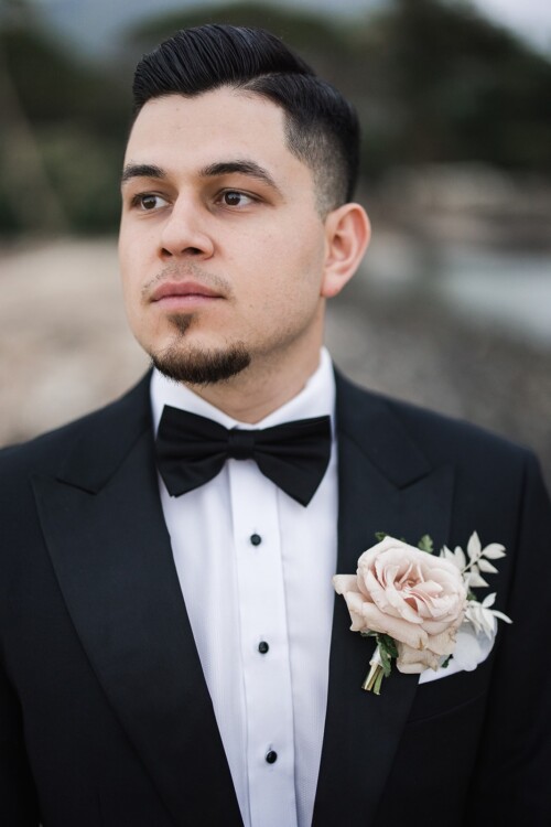 Matias Ezcurra Photography, Groom in black tuxedo with bow tie and boutonniere, looking off to the side.